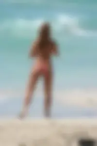 Topless girl in a tiny thong on the beach playing paddle ball