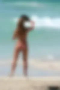 Topless girl in a tiny thong on the beach playing paddle ball