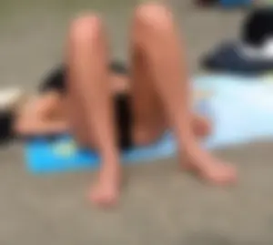 Lady in black bikini showing some pubes while laying out
