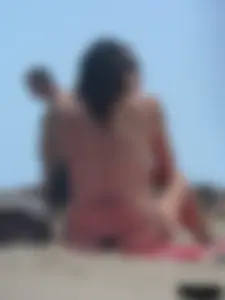 Brunette lady topless and in a black thong on the beach