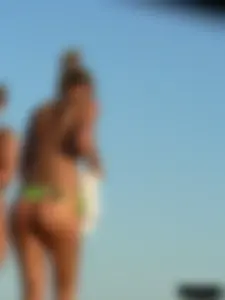 Topless girl on the beach with small boobs wearing a green thong bikini