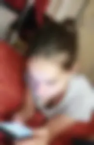 Downblouse peek of a cute girl lying in bed with her phone