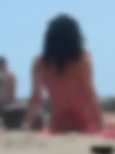 Brunette lady topless and in a black thong on the beach