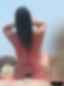 Brunette lady topless and in a black thong on the beach