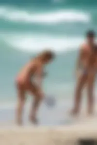 Topless girl in a tiny thong on the beach playing paddle ball