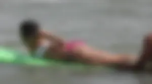Brunette bikini girl on the beach and surfing in her bikini