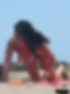 Brunette lady topless and in a black thong on the beach