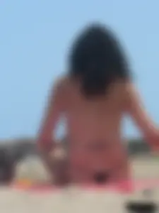 Brunette lady topless and in a black thong on the beach