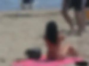 Brunette lady topless and in a black thong on the beach