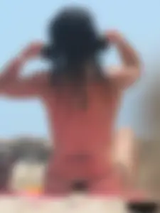 Brunette lady topless and in a black thong on the beach