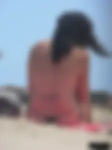 Brunette lady topless and in a black thong on the beach