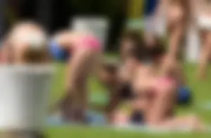 Group of teens in swimsuits sunbathing in the park