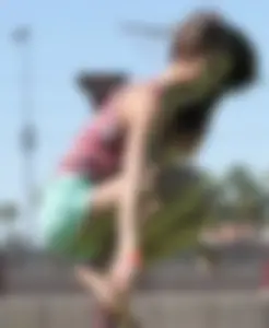Brunette skinny teen in green shorts playing in a bounce house