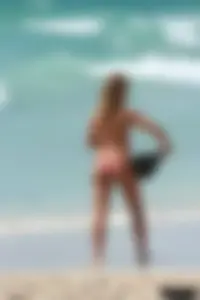 Topless girl in a tiny thong on the beach playing paddle ball