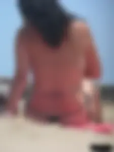 Brunette lady topless and in a black thong on the beach