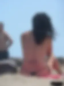 Brunette lady topless and in a black thong on the beach