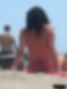 Brunette lady topless and in a black thong on the beach