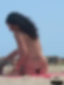 Brunette lady topless and in a black thong on the beach
