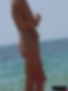 Topless skinny blonde lady in a g-string bikini at the beach