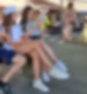 Candid Teens in Shorts And Sneakers Sitting on the Street Bench