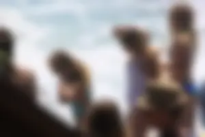 Blonde in blue thong swimsuit on the beach with friends
