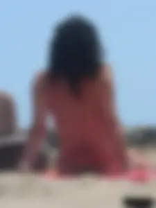 Brunette lady topless and in a black thong on the beach