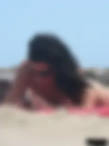 Brunette lady topless and in a black thong on the beach