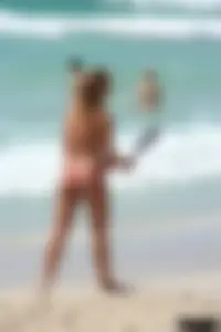 Topless girl in a tiny thong on the beach playing paddle ball