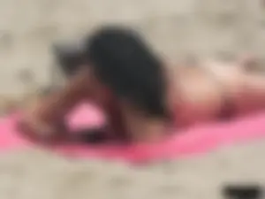Brunette lady topless and in a black thong on the beach