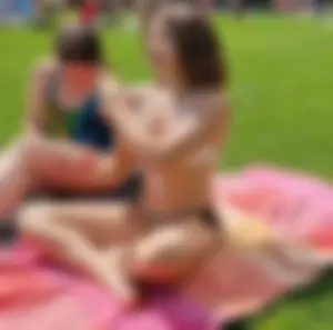 Young Candid Girl in a Swimsuit Sitting With Crossed Legs on the Grass at the Beach Creepshots
