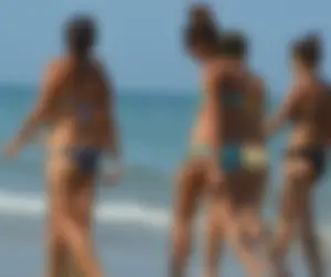 Foursome bikini friends walking the beach