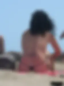 Brunette lady topless and in a black thong on the beach