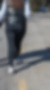 A beautiful little brunette walking in the park. tight black leggings