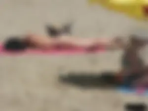 Brunette lady topless and in a black thong on the beach