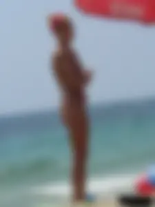 Topless skinny blonde lady in a g-string bikini at the beach