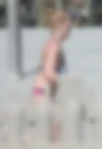 Skinny blonde girl on the beach in her pink and white bikini