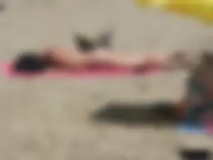 Brunette lady topless and in a black thong on the beach