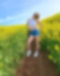 Smiling non-candid cutie wearing denim shorts in the middle of a field of flowers