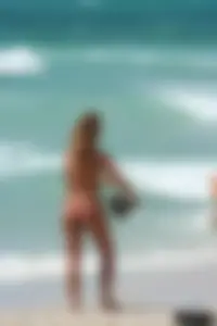 Topless girl in a tiny thong on the beach playing paddle ball