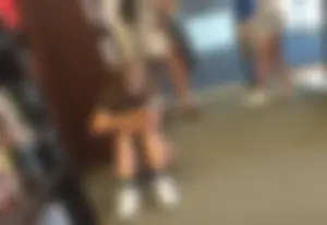 Cute skinny teen in shorts sitting on the floor at the book store
