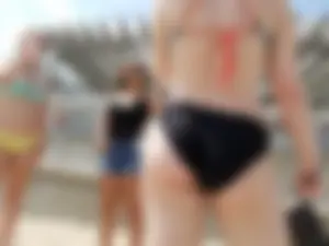 Sexy beach babe in yellow and blue bikini with friends