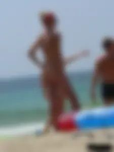 Topless skinny blonde lady in a g-string bikini at the beach