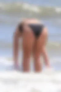 Beach blonde in the water in black bikini with a nice ass and small boobs