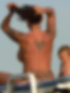 Topless tattooed lady on the beach with fake big tits
