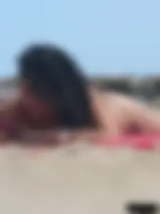 Brunette lady topless and in a black thong on the beach
