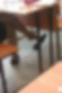 Bored College Girl in a Short Dress And Flats Lying On Desk And Playing With Her Shoe in a Classroom