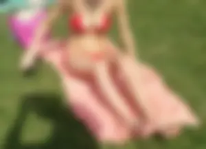 Skinny Girl in Red Swimsuit Sitting on the Grass Applying Sun Lotion Candid Pics