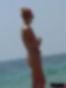 Topless skinny blonde lady in a g-string bikini at the beach
