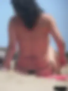 Brunette lady topless and in a black thong on the beach