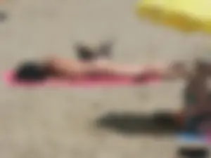 Brunette lady topless and in a black thong on the beach